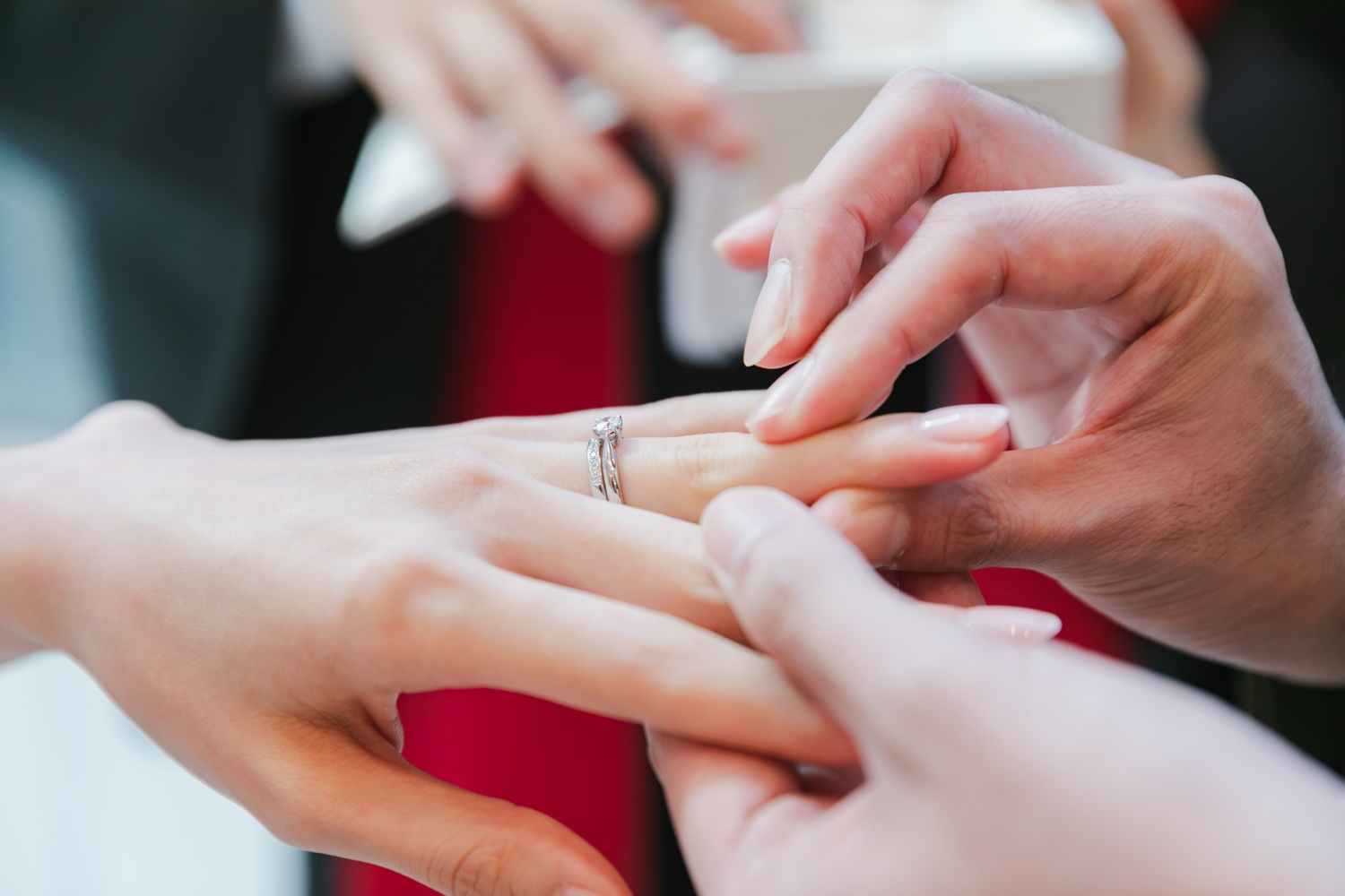男性が女性の左手に婚約指輪をはめる瞬間